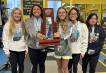 a group of girls standing next to each other holding a trophy