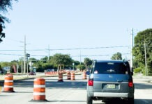 a blue van driving down a street next to orange traffic cones