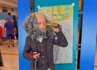 a child dressed in a wig and holding a wine bottle