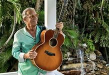 a man holding a guitar in front of a fountain