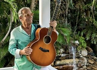 a man holding a guitar in front of a fountain