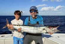 a man and a boy on a boat holding a fish