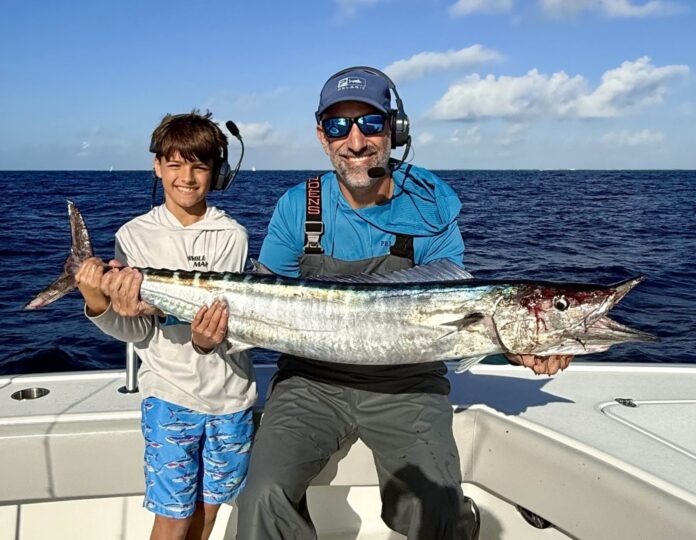 a man and a boy on a boat holding a fish