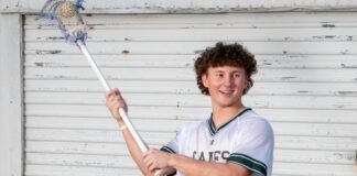 a young man holding a lacrosse stick in front of a building