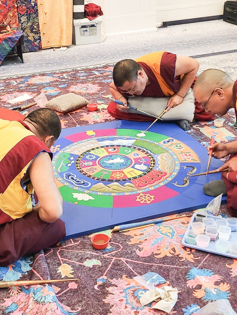 a group of monks painting a picture on the ground