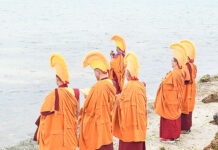 a group of people standing on top of a beach next to a body of water