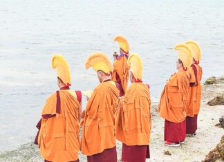 a group of people standing on top of a beach next to a body of water