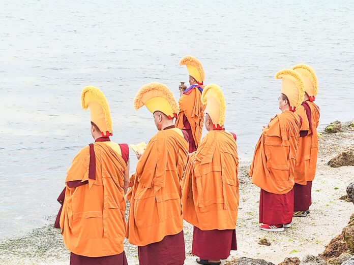 a group of people standing on top of a beach next to a body of water