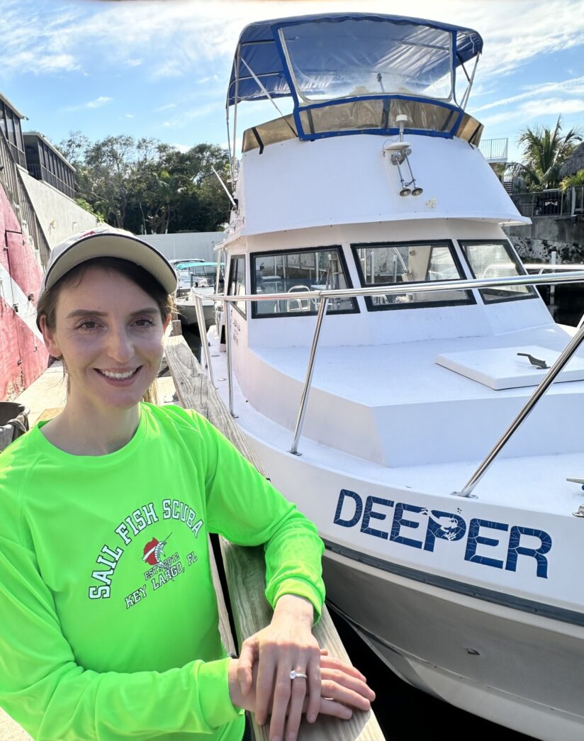 a woman sitting on a dock next to a boat