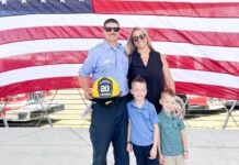 a man and woman and two children standing in front of an american flag