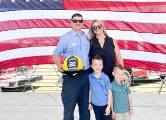 a man and woman and two children standing in front of an american flag