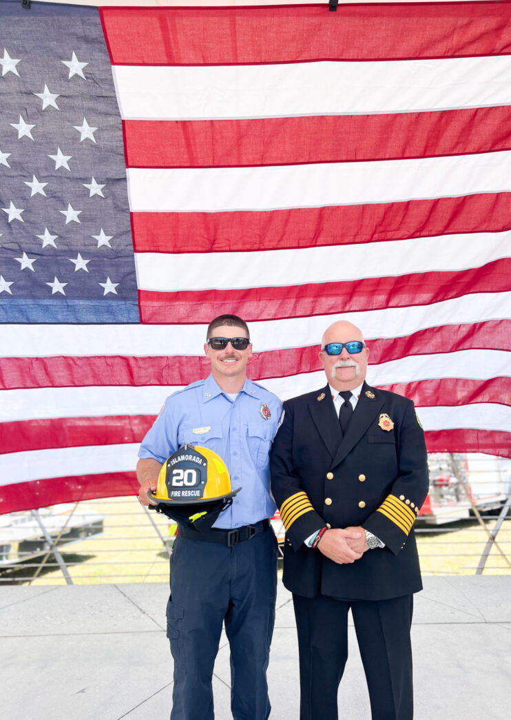 a couple of men standing next to each other in front of an american flag