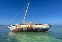 a rusted boat sitting in the middle of the ocean