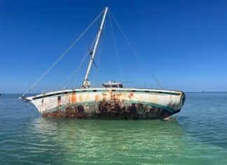 a rusted boat sitting in the middle of the ocean