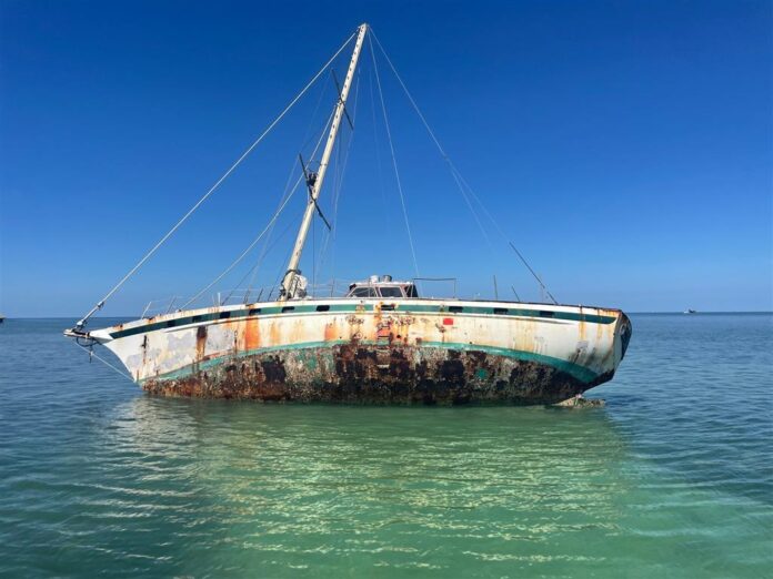 a rusted boat sitting in the middle of the ocean