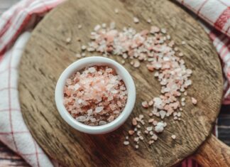 a bowl of sea salt on a wooden cutting board
