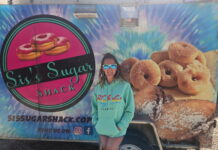 a woman standing in front of a doughnut truck