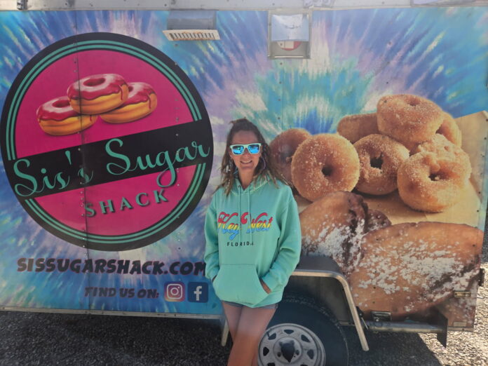 a woman standing in front of a doughnut truck