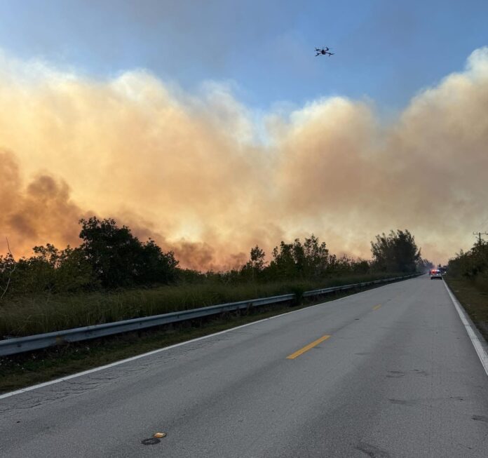 a large plume of smoke is seen from the road