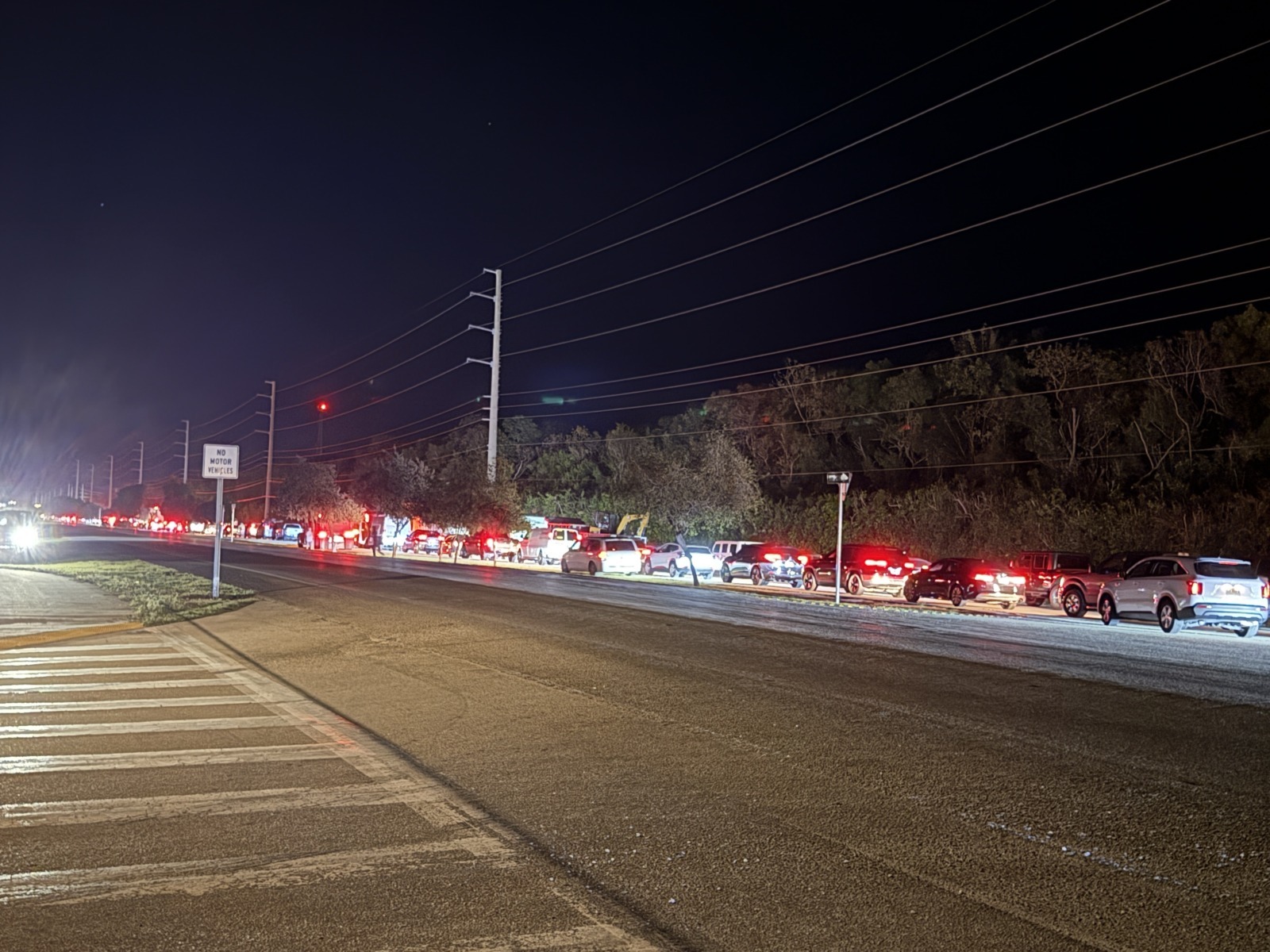 a city street at night with cars parked on the side of the road