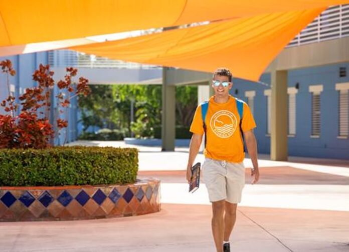 a man walking down a sidewalk wearing a yellow shirt