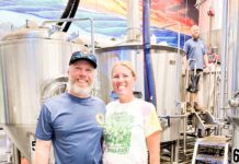 a man and a woman standing in front of a brewery