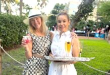 a couple of women standing next to each other holding drinks