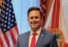 a man in a suit and tie standing in front of flags