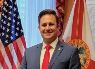 a man in a suit and tie standing in front of flags