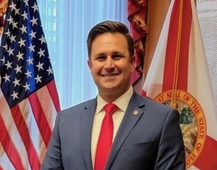 a man in a suit and tie standing in front of flags