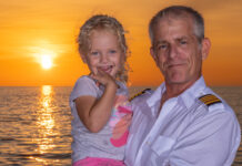 a man and a little girl on a boat at sunset