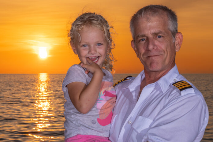 a man and a little girl on a boat at sunset