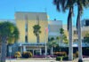 a yellow building with palm trees in front of it