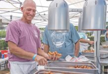 a couple of men standing over trays of food