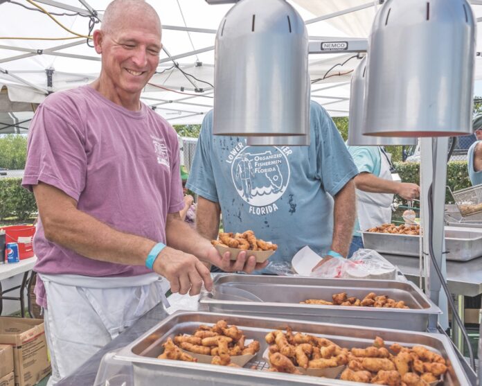 a couple of men standing over trays of food