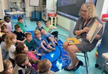 a woman reading a book to a group of children