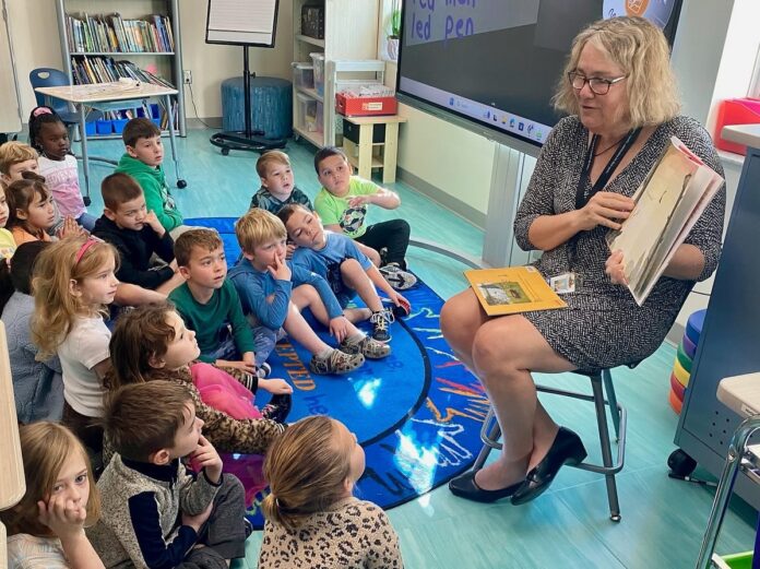 a woman reading a book to a group of children