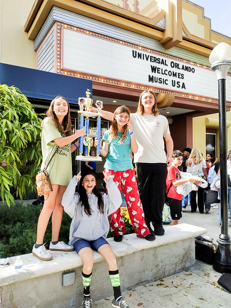 a group of girls posing for a picture in front of a theater