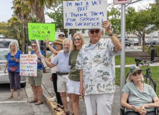 a group of people standing on a sidewalk holding signs