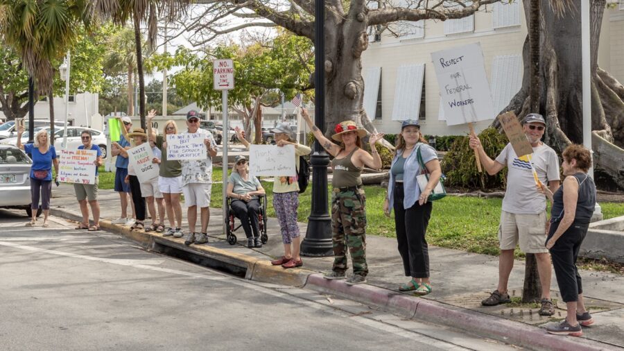 a group of people standing on the side of a road holding signs