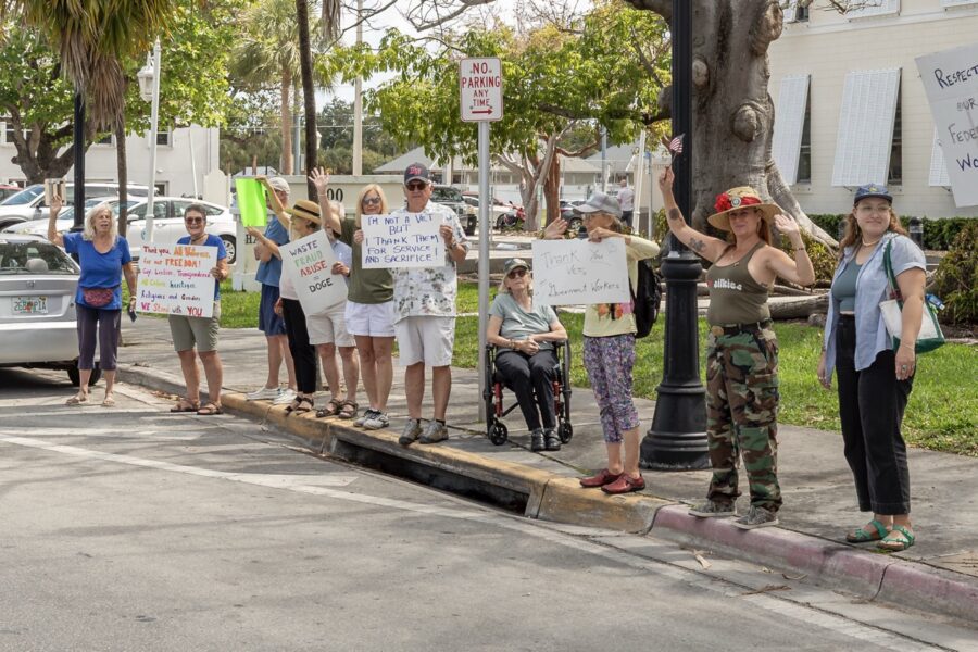 a group of people standing on the side of a road holding signs