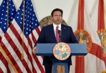 a man standing at a podium in front of flags