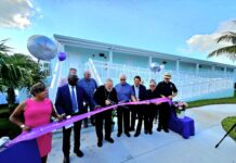 a group of people cutting a ribbon in front of a building