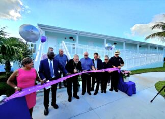 a group of people cutting a ribbon in front of a building