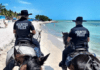 two police officers riding horses on a beach