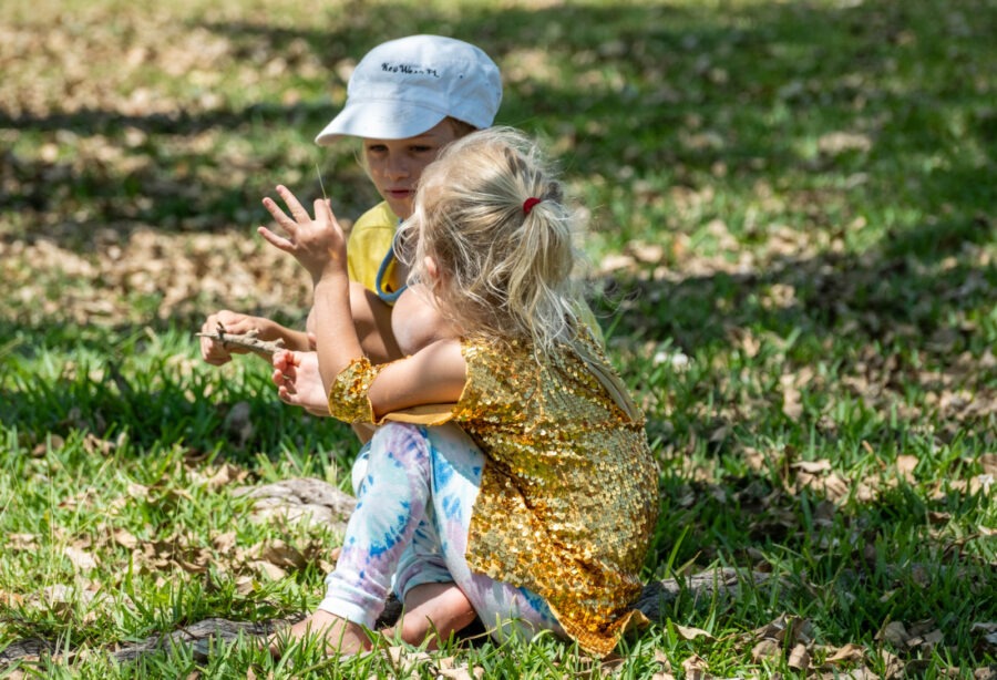 two little girls sitting in the grass playing with a frisbee