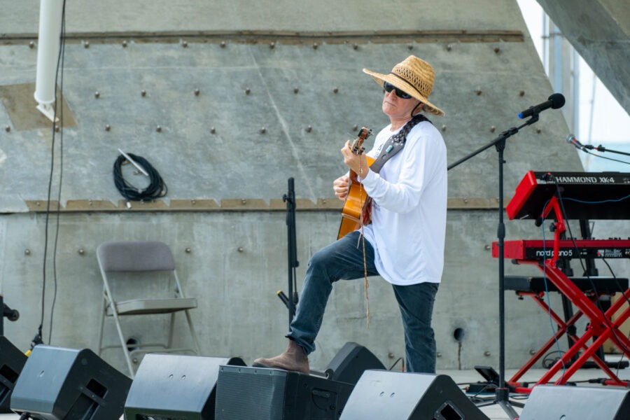 a man in a straw hat playing a guitar on stage