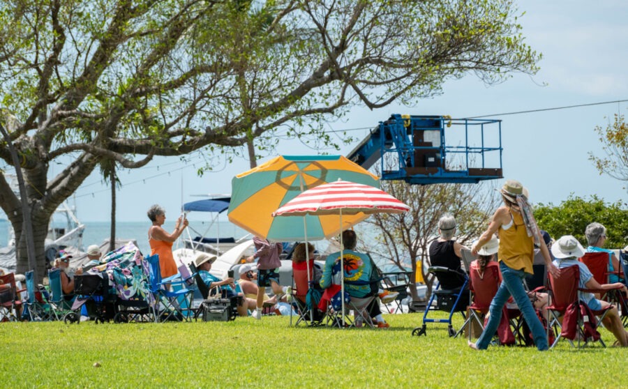 a group of people sitting in lawn chairs under umbrellas