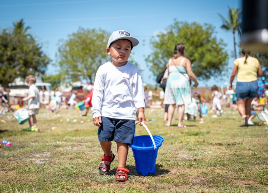 a young boy holding a blue bucket in a field