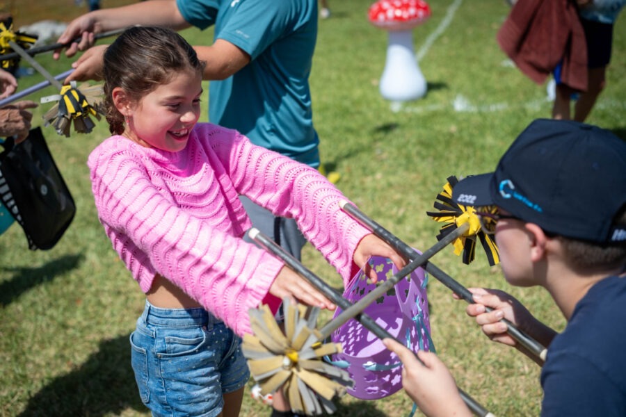 a little girl is holding a purple pinwheel